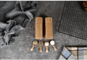 Due macinapepe manuali in legno di quercia con quattro cucchiai per spezie su piano in cemento