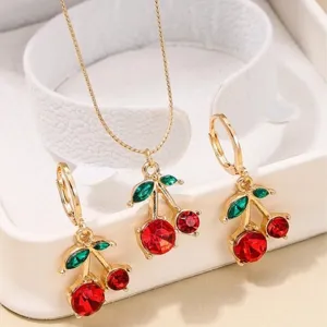 Close-up of gold cherry jewelry set featuring red and green faceted crystals