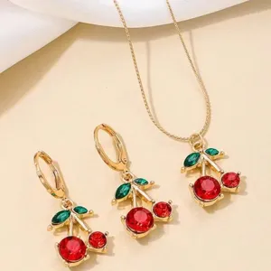Detailed macro shot of elegant gold cherry jewelry set featuring red crystal fruits