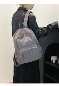 Vue arrière d'un élégant sac à dos en nylon gris imperméable porté par un modèle.