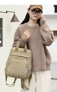Close-up of stylish quilted khaki diaper bag worn by model in minimalist setting