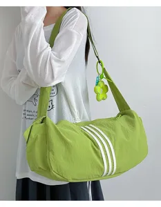 Nahaufnahme einer lindgrünen Sporttasche mit weißen Streifen und einem Blumenanhänger-Accessoire