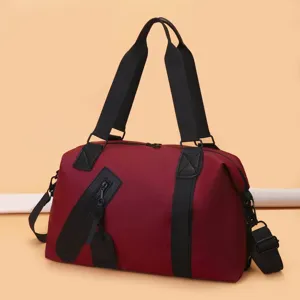 Vue latérale d'un grand sac de voyage bordeaux avec sangles noires pour le sport ou le voyage.
