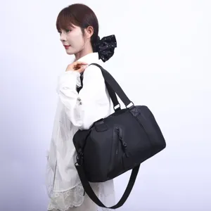 Modèle portant un grand sac de voyage noir pour les voyages courts et le sport.