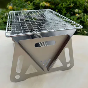 Close-up of portable stainless steel folding BBQ grill for outdoor camping setup.