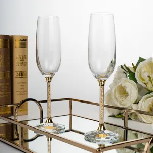 Close-up detail of elegant crystal champagne flutes featuring gold crystal filled stems