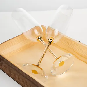 Detail view of luxury crystal champagne flutes with gold foil filled stems in a wooden box