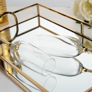 Close-up of elegant champagne flutes with gold foil stems on a mirrored tray