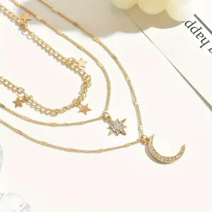 Close-up of golden multi-layered necklace with rhinestone star and moon pendants