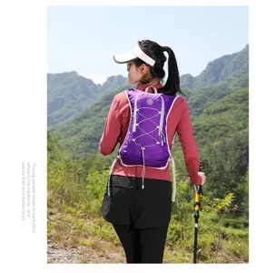 Purple running hydration vest backpack worn by a model in an outdoor mountain scene.