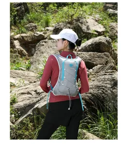 Back view of a professional grey and blue hydration running vest worn by a woman outdoors