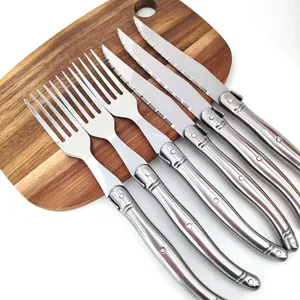 Modernes Besteckset aus Edelstahl mit Steakmessern und Gabeln auf Holzbrett