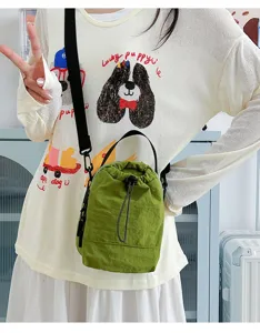 Green lightweight outdoor drawstring bucket bag used as a versatile crossbody phone carrier