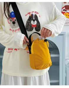 Detailed shot of yellow lightweight outdoor crossbody bag holding a water bottle