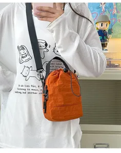 Detail view of orange lightweight outdoor crossbody bag with drawstring on model