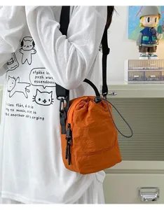 Close-up of a bright orange lightweight outdoor crossbody bag with a drawstring closure