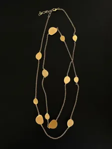 Close-up view of a designer long necklace with elegant brushed gold disks