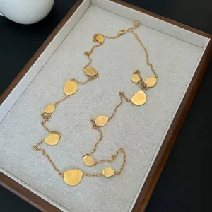 Macro detail view of a long brushed gold disc necklace on a textured display tray