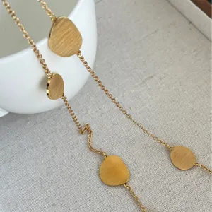 Detailed macro shot of gold brushed metal discs on a long elegant chain necklace