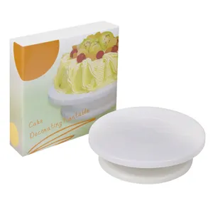 Close-up view of a white cake decorating turntable next to its colorful product packaging