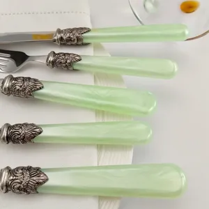 Detail von Vintage-Edelstahlbesteck mit mintgrünen Griffen und verzierten Zwingen.