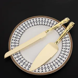 Nahaufnahme von goldenem Hochzeitstortenmesser und Schaufel Set mit Kristallherz