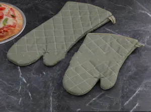 Green quilted heat-resistant oven mitts and pot holder set on dark marble surface detail view