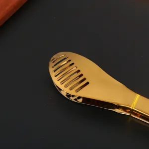 Detailed close-up of golden stainless steel food tongs with a slotted head for kitchen use