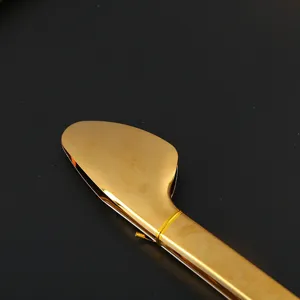 Close-up detail showing the head of a large golden stainless steel kitchen food tong
