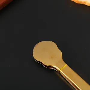 Close-up detail of golden stainless steel food tongs with smooth metallic finish