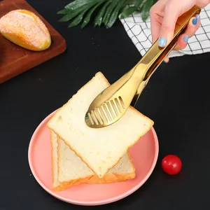 Detailed view of golden stainless steel food tongs picking up a slice of fresh toast bread.