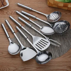 Stainless steel kitchen utensil set with spatulas and ladles on a wooden desk