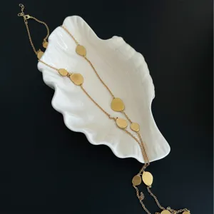 Detailed close-up view showing the textured brushed finish of gold discs on this long necklace.