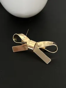 Detailansicht einer minimalistischen goldenen 3D-Schleifenbrosche mit polierter Oberfläche