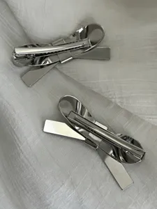 Detailansicht der Rückseite von silbernen Metall-Schleifen-Haarspangen auf weißem Stoff