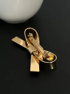 Detaillierte Makroansicht der stabilen Metallclip-Mechanik eines goldenen 3D-Bogen-Haarschmucks.