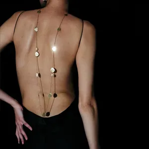Detailed rear view of a model wearing a long gold necklace with brushed disk pendants