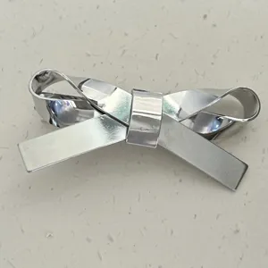 Detailansicht einer minimalistischen, silberfarbenen 3D-Schleife als Haarspange.
