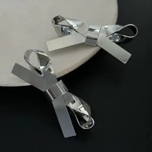 Minimalistische 3D-Haarspangen in Silberoptik mit Schleifen-Design auf schwarzem Grund.