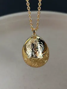 Nahaufnahme eines goldenen eiförmigen Anhängers im Vintage-Stil mit Blumenmuster