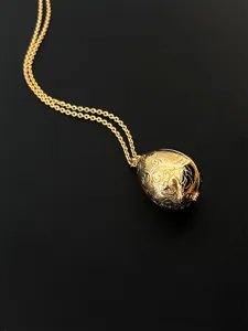 Detailansicht eines goldenen Vintage-Anhängers in Ei-Form mit feinen Gravuren.