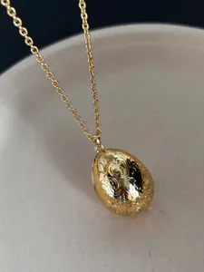 Nahaufnahme eines goldenen Eianhängers im Vintage-Stil mit floralen Gravurmustern