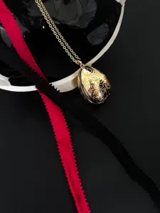 Nahaufnahme eines goldenen Medaillons in Eiform mit filigranen Gravuren im Vintage-Stil
