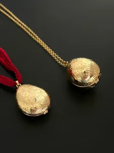 Detailansicht eines goldenen Eianhängers im Vintage-Stil mit feinem Reliefmuster