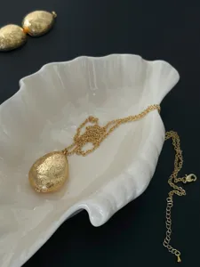 Detailansicht einer goldenen Vintage-Halskette mit eiförmigem Medaillon und Gravur