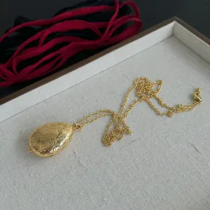 Makroansicht eines goldenen Vintage-Anhängers in Eiform mit feinen floralen Reliefmustern