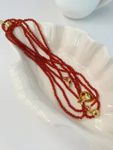 Close-up macro detail of red agate beaded necklace with vintage gold trumpet pendants