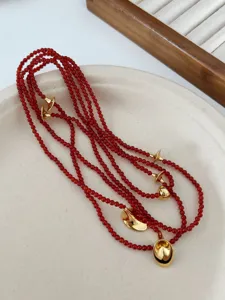 Close-up view of a long red agate beaded necklace with vintage gold trumpet accents.