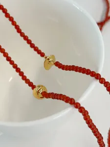 Close-up macro detail of a red agate beaded necklace with vintage gold trumpet accents