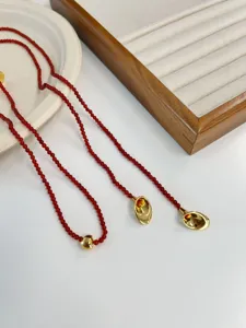 Close-up detail of red agate beaded long necklace with vintage gold trumpet pendants
